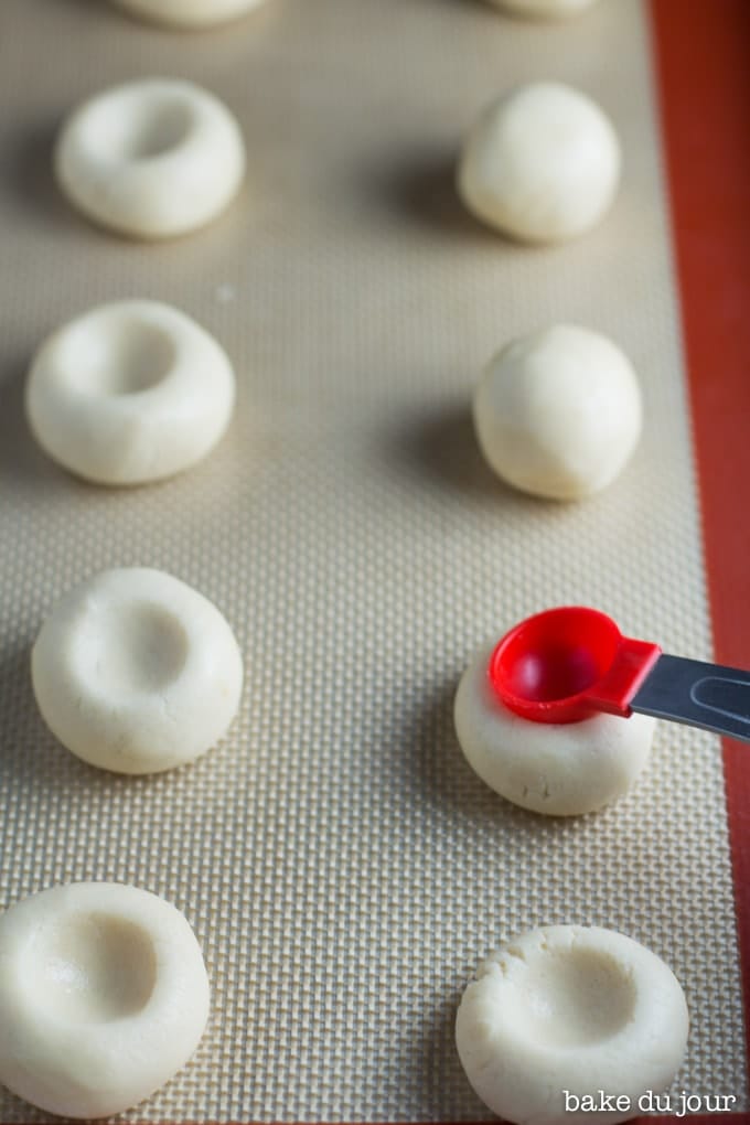 Strawberry Jam Thumbprint Cookies dough being pressed into thumbprints