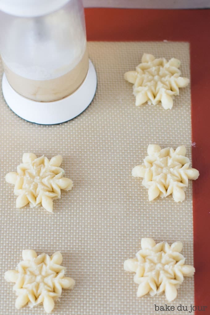 Using the cookie press to press out the cookie dough