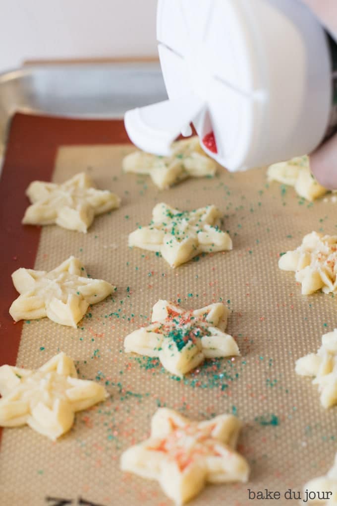 Topping the Holiday Spritz Cookies with sprinkles