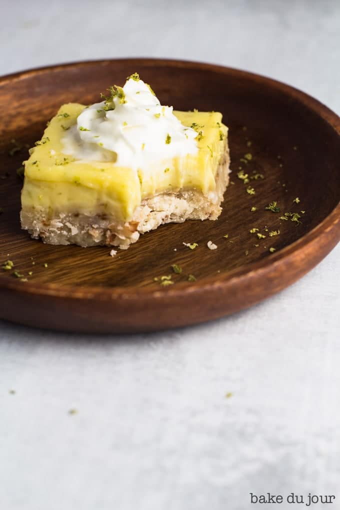 A serving of Coconut Lime Bar on a small wooden plate, with a bite taken out of it!