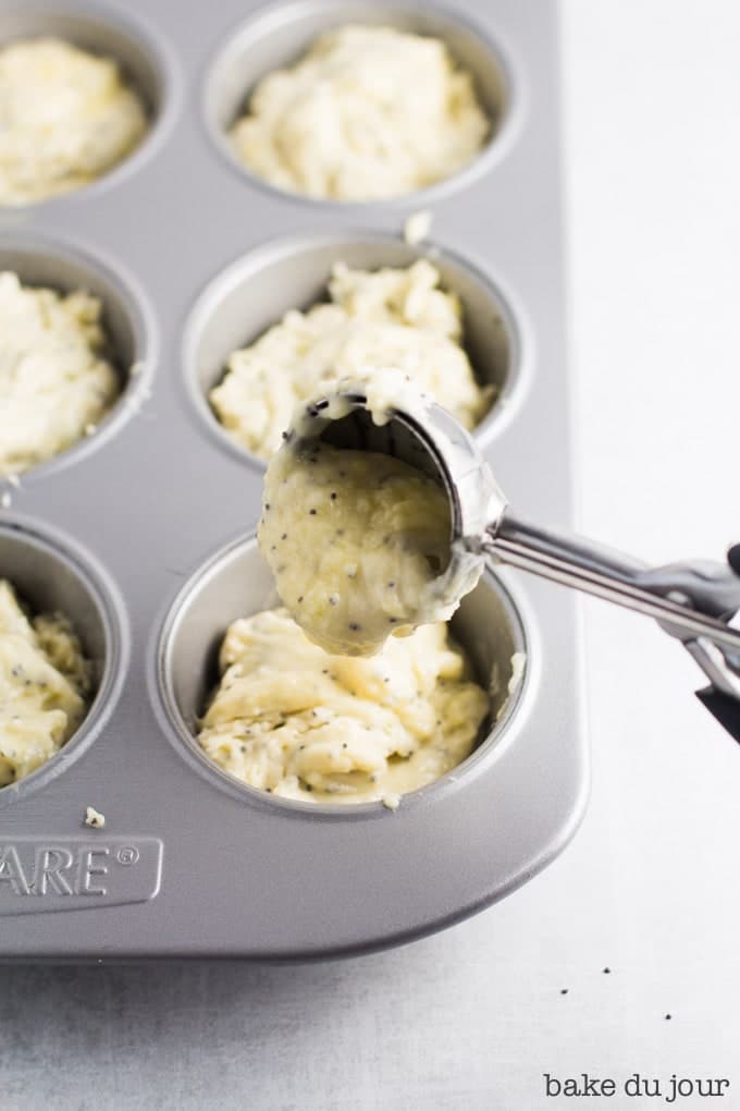 Using a medium cookie scoop to fill the cavities of a muffin pan 3/4 of the way with batter