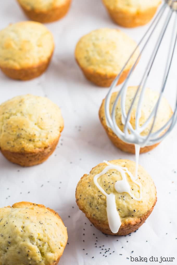 Using a whisk to apply the lemon glaze to each muffin