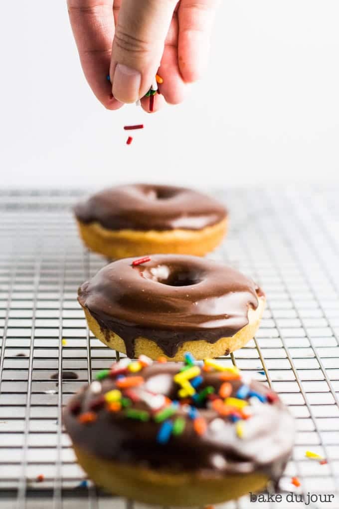 A set of 3 chocolate frosted doughnuts. Adding some sprinkles over the middle doughnut!