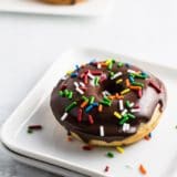 A Chocolate Frosted Doughnut on a square white dish