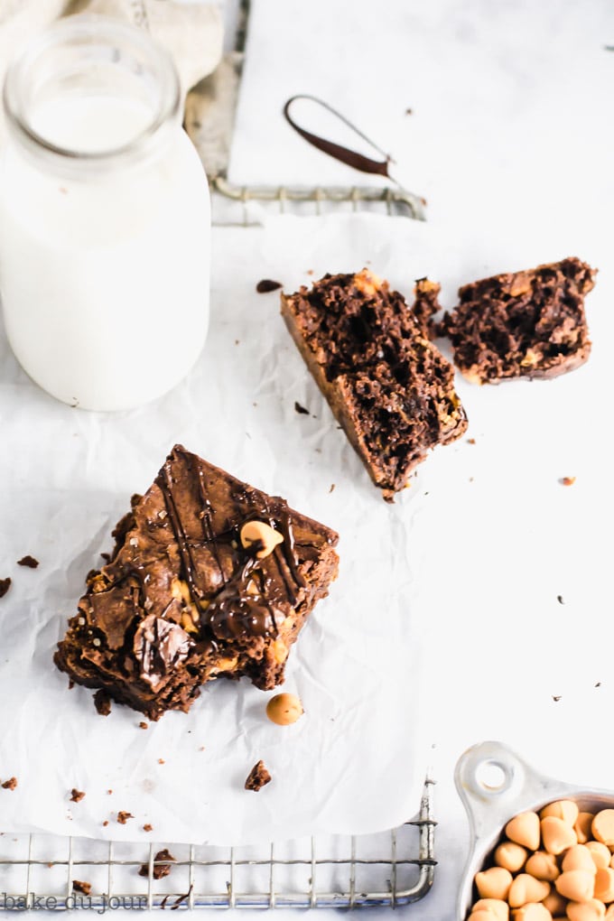 A brownie with a bite taken out of it with a jug of milk in the background