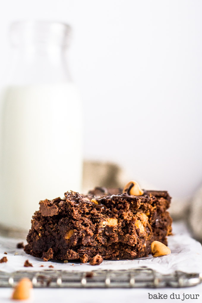 A bite taken out of a brownie with a jug of milk in the background