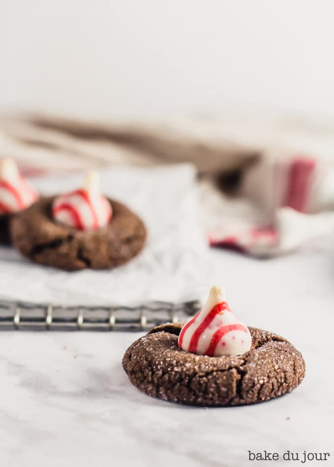 A Chocolate Peppermint Blossom Cookie in the foreground with two cookies in the background on a cooling rack